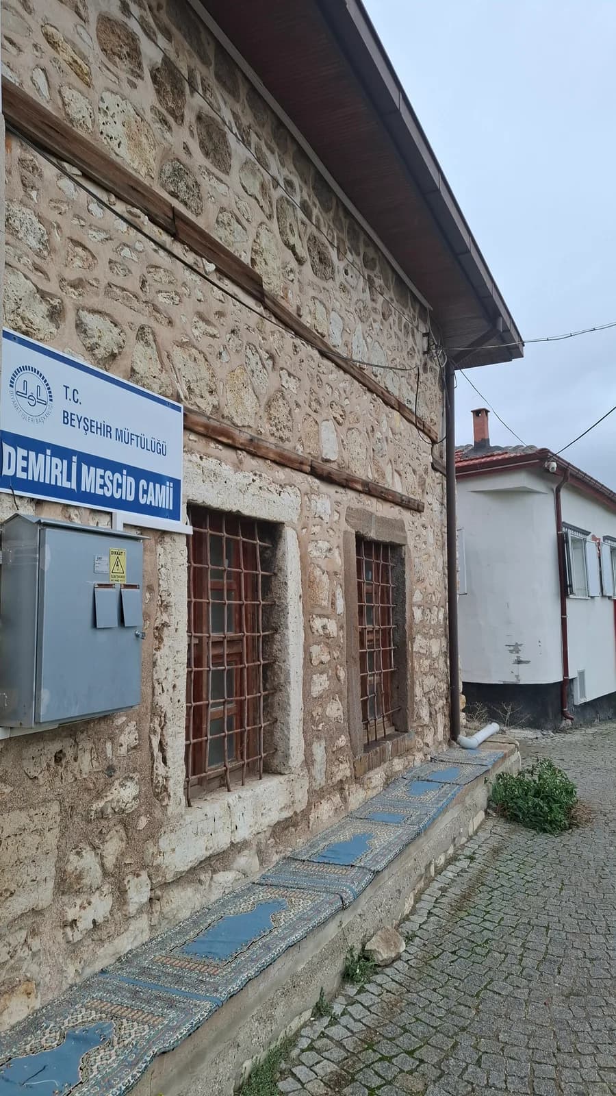 Demirli Mescid’in taş duvarı, ahşap hatılları ve demir parmaklıklı penceresi.